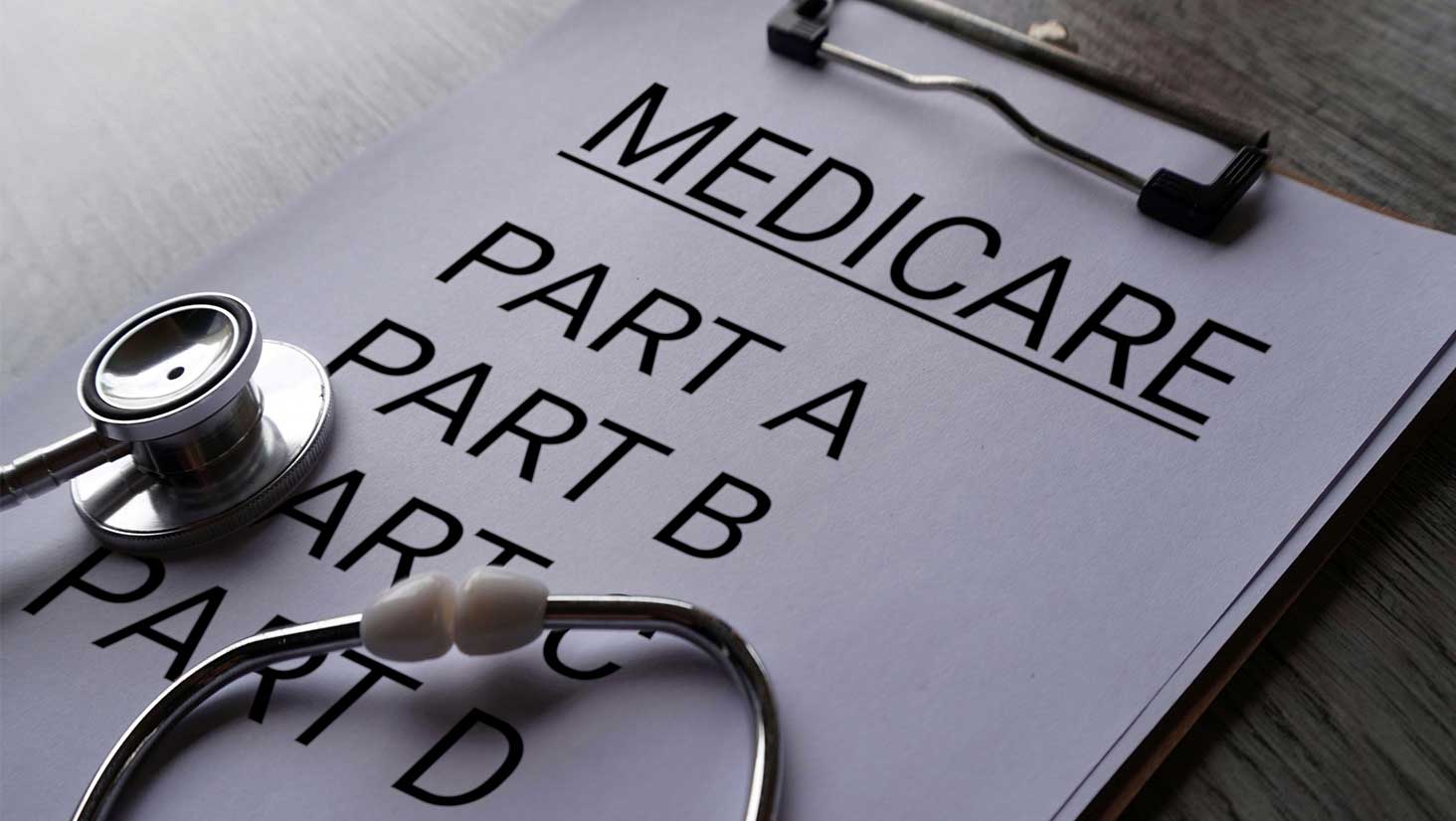 Photo showing a clipboard with Medicare Enrollment for Part A, Part B, Part C, and Part D