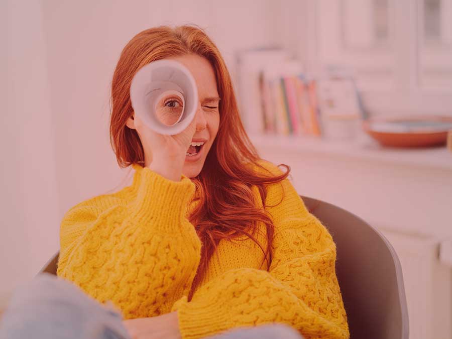 Girl in yellow sweater using her resume as a viewing glass