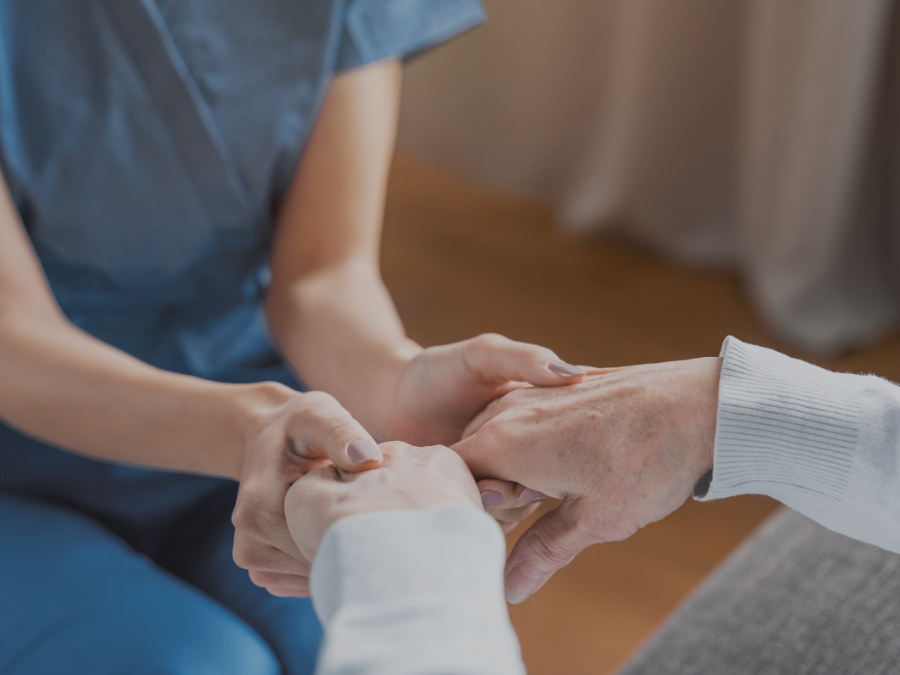 Assisting senior people Close up of female caregiver holding elderly womans hands indoors